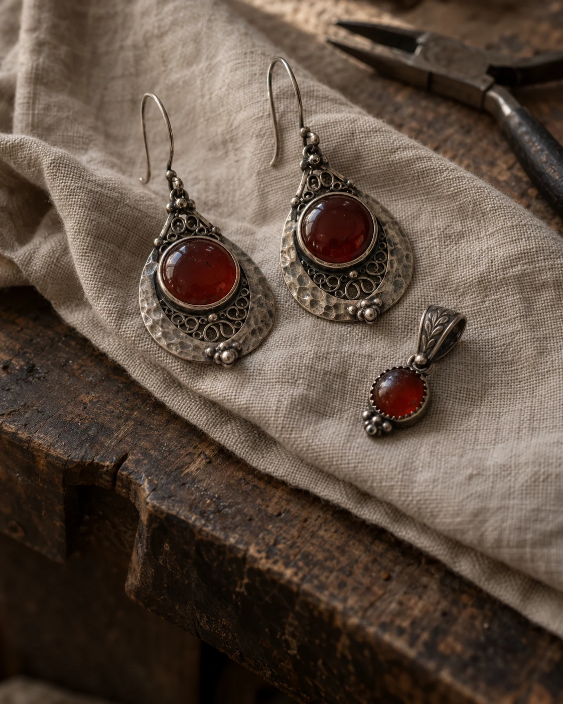 Editorial scene of silver jewelry with red stones on natural fabric